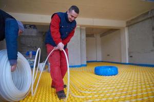 trabajadores instalando sistema de calefacción por suelo radiante foto