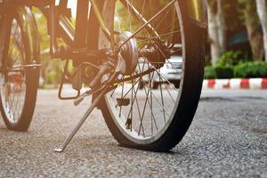 Closeup view of rear wheel of old bicycle which is flat and parked on pavement in the public park, soft and selective focus. photo