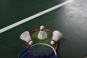 Cream white badminton shuttlecocks and rackets on green floor in indoor badminton court photo