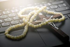 Metal cross necklace on notebook keyboard, soft and selective focus on cross necklace. photo