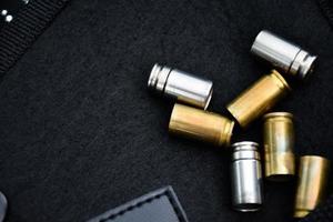 9mm pistol bullets and bullet shells on black leather background, soft and selectivec focus. photo