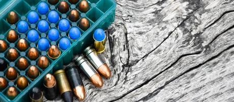 9mm pistol bullets and bullet shells on wooden table, soft and selectivec focus. photo