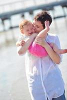 mamá y bebé en la playa se divierten foto