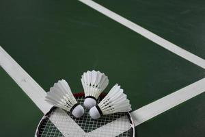 Cream white badminton shuttlecocks and rackets on green floor in indoor badminton court photo