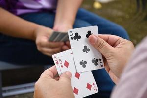 Poker paper cards in hands of woman who sitting and playing card with friend, soft and selective focus, freetimes and hobby activity at home concept. photo