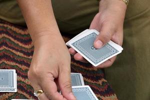 Poker paper cards in hands of woman who sitting and playing card with friend, soft and selective focus, freetimes and hobby activity at home concept. photo