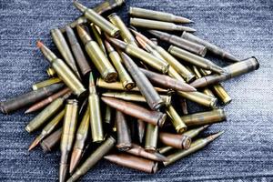 Pile of old bullets on wooden plank and jeans, soft and selective focus. photo