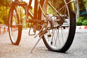 Closeup view of rear wheel of old bicycle which is flat and parked on pavement in the public park, soft and selective focus. photo