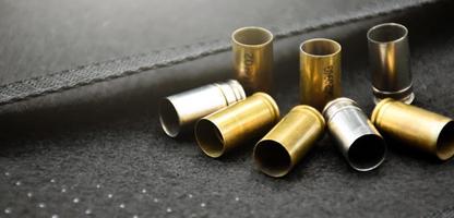 9mm pistol bullets and bullet shells on black leather background, soft and selectivec focus. photo