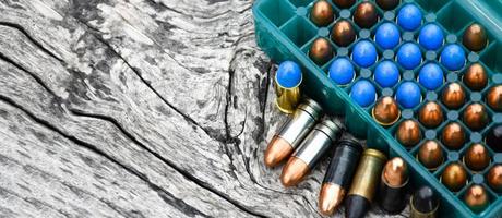 9mm pistol bullets and bullet shells on wooden table, soft and selectivec focus. photo