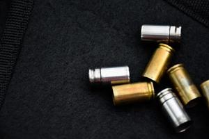 9mm pistol bullets and bullet shells on black leather background, soft and selectivec focus. photo