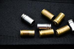 9mm pistol bullets and bullet shells on black leather background, soft and selectivec focus. photo