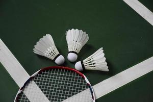 volantes y raquetas de bádminton blanco crema en el suelo verde en la cancha de bádminton cubierta foto