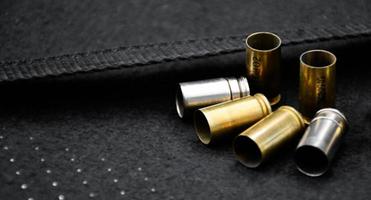 9mm pistol bullets and bullet shells on black leather background, soft and selectivec focus. photo