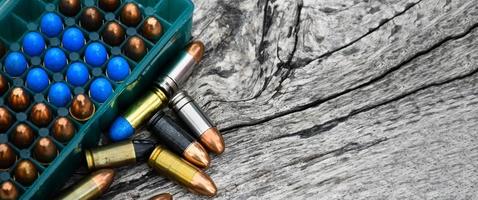 9mm pistol bullets and bullet shells on wooden table, soft and selectivec focus. photo