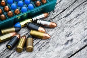 9mm pistol bullets and bullet shells on wooden table, soft and selectivec focus. photo