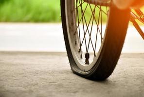 rueda trasera de bicicleta plana y estacionada en el pavimento al lado de la carretera. foto