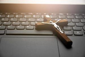 Metal cross necklace on notebook keyboard, soft and selective focus on cross necklace. photo