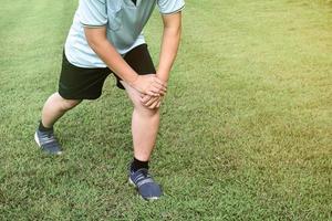 Middle aged asian man runner stretching on the grass lawn relaxing after and before running in the park. Healthy lifestyle with outdoor exercising concept photo