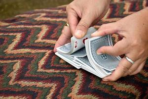 Poker paper cards in hands of woman who sitting and playing card with friend, soft and selective focus, freetimes and hobby activity at home concept. photo