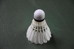 Cream white badminton shuttlecocks and rackets on green floor in indoor badminton court photo
