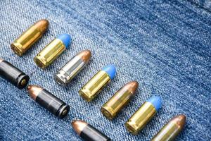 9mm pistol bullets and bullet shells on blue jeans, soft and selectivec focus. photo