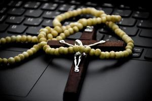Metal cross necklace on notebook keyboard, soft and selective focus on cross necklace. photo