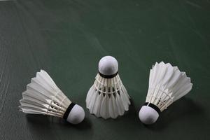 Cream white badminton shuttlecocks and rackets on green floor in indoor badminton court photo