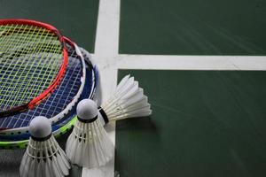 Cream white badminton shuttlecocks and rackets on green floor in indoor badminton court photo