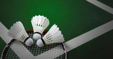 Cream white badminton shuttlecocks and rackets on green floor in indoor badminton court photo