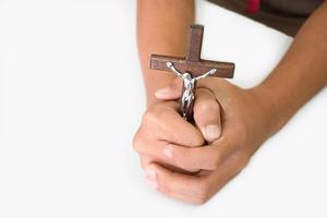 cruz de madera con una estatua de jesús crucificado por su brazo sosteniendo en manos de oración sobre una mesa blanca en la iglesia, enfoque suave y selectivo. foto