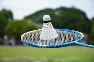 Badminton racket and badminton shuttlecock against cloudy and bluesky background, outdoor badminton playing concept. selective focus on racket. photo