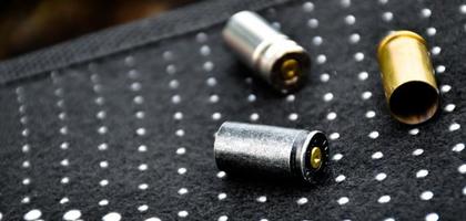 9mm pistol bullets and bullet shells on black leather background, soft and selectivec focus. photo