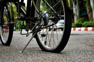 Closeup view of rear wheel of old bicycle which is flat and parked on pavement in the public park, soft and selective focus. photo