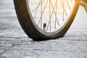 rueda trasera de bicicleta plana y estacionada en el pavimento al lado de la carretera. foto