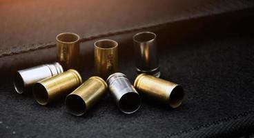 9mm pistol bullets and bullet shells on black leather background, soft and selectivec focus. photo