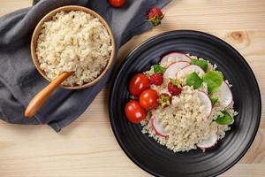 Quinoa salad with vegetables, raspberry and tomatoes on the wooden table. Super food for healthy and concept of balanced diet photo