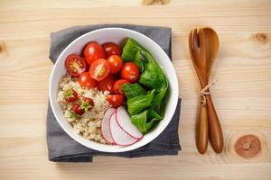 Quinoa salad with vegetables, raspberry and tomatoes on the wooden table. Super food for healthy and concept of balanced diet photo