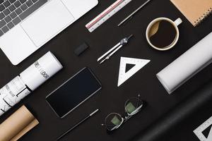 Creative flat lay of architects black table with roll blueprints, architectural project plan, engineering tools, office supplies, laptop computer and a cup of hot coffee,Workspace for designer concept