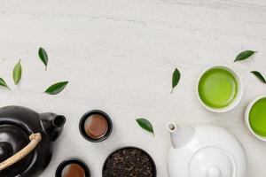 taza de té caliente con tetera, hojas de té verde y hierbas secas vista superior en el espacio vacío de la mesa de piedra blanca, producto orgánico de la naturaleza para la salud con estilo tradicional foto
