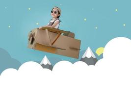 Asian little child girl playing with cardboard toy airplane handicraft over the clouds with copy space for your text, Creative at home and dreams of flight concept photo