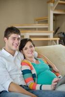 pregnant couple at home using tablet computer photo