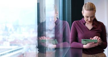 bonita mujer de negocios usando tableta en el edificio de oficinas junto a la ventana foto