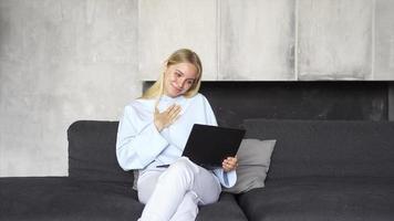 Young blonde woman on a couch uses a smart device video