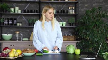 jong vrouw in een keuken met vers ingrediënten en slim telefoon apparaat video