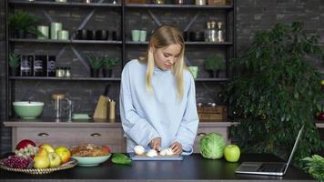 jovem em uma cozinha com ingredientes frescos e dispositivo de telefone inteligente video