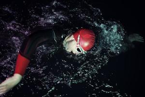 real triathlon athlete swimming in dark night photo