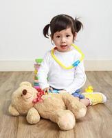 Little asian girl or a little cute asian girl doctor examining teddy bear photo