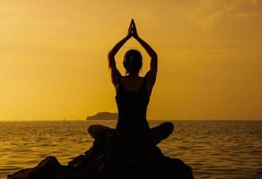 mujer meditando en la playa al atardecer foto