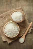 Jasmine rice in bowl and sack on wooden table photo